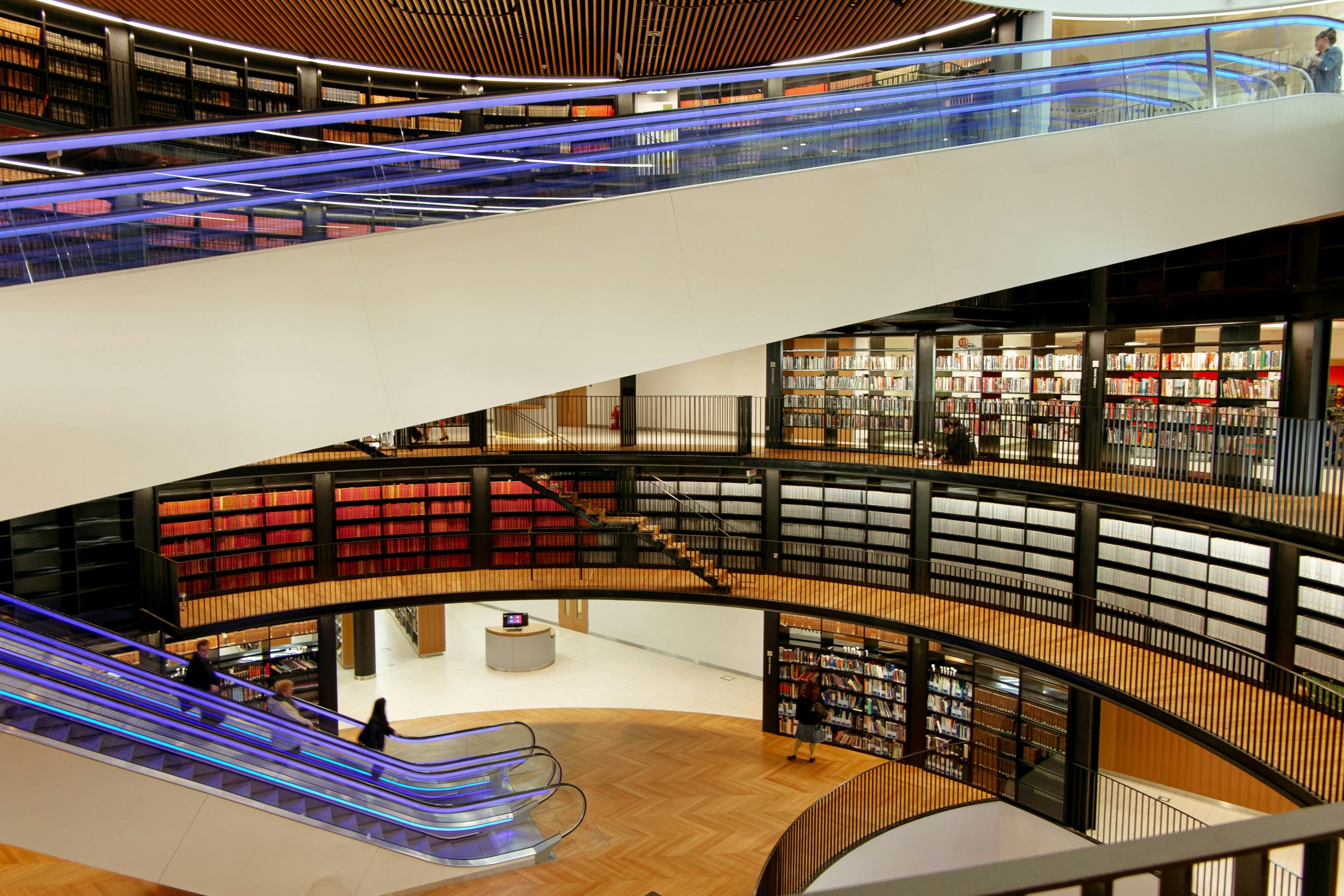 A spacious library with bookshelves, escalators, and modern design elements.